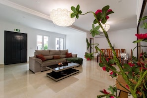 A modern living room with a sofa, coffee table, and decorative plants.