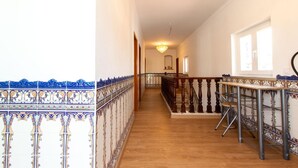 A corridor with a wooden floor, a railing with intricate blue and white tile patterns, and a chandelier. - Spacious 5-Bedroom Villa with Garden Near Lisbon ,Sesimbra& beautiful beaches (Quinta Do Conde)