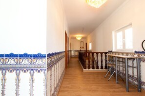 A corridor with a wooden floor, a railing with intricate blue and white tile patterns, and a chandelier. - Spacious 5-Bedroom Villa with Garden Near Lisbon ,Sesimbra& beautiful beaches (Quinta Do Conde)