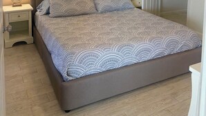 A bedroom with a bed, nightstands, a ceiling fan, a painting, and a wardrobe. - Two Bed Two Bath Seminole Stay (Seminole)