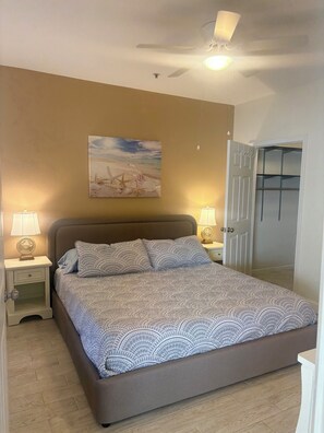 A bedroom with a bed, nightstands, a ceiling fan, a painting, and a wardrobe. - Two Bed Two Bath Seminole Stay (Seminole)