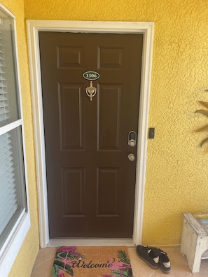 A brown door with a number plate, a doormat, and a pair of shoes on the ground. - Two Bed Two Bath Seminole Stay (Seminole)