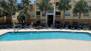 A swimming pool with lounge chairs and a building with balconies in the background. - Two Bed Two Bath Seminole Stay (Seminole)