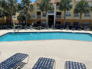 A swimming pool with lounge chairs and a building with balconies in the background. - Two Bed Two Bath Seminole Stay (Seminole)