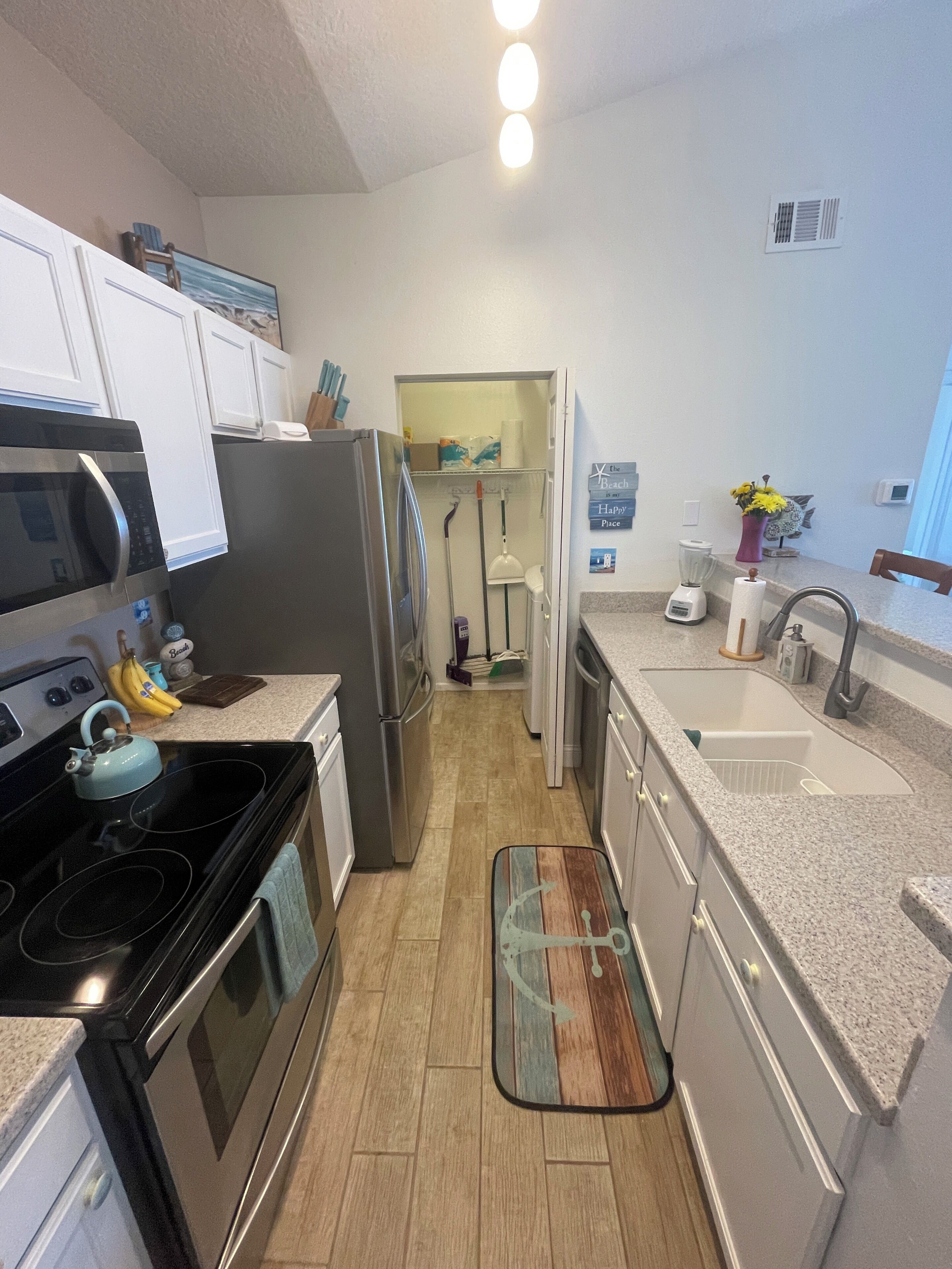 A kitchen with a stove, microwave, refrigerator, and a countertop with a blender and a vase of flowers.