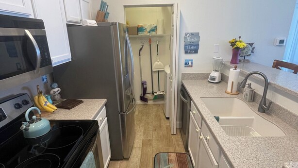 A kitchen with a stove, microwave, refrigerator, and a countertop with a blender and a vase of flowers. - Two Bed Two Bath Seminole Stay (Seminole)