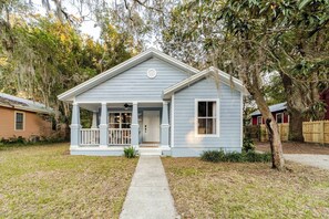 A single-story house with a front porch, a visible door, and a small window. - The Designer Boutique • 3BR/2BA by UF • Firepit (Gainesville)