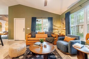 Ein Wohnzimmer mit einer Couch, Sesseln, einem Couchtisch und einem Essbereich mit Tisch und Stühlen.