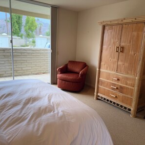 Ein Schlafzimmer mit einem großen Bett, einem roten Sessel und einem Holzschrank.