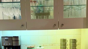 Una cucina con una macchina da caffè, un vassoio di legno e bicchieri in mostra.