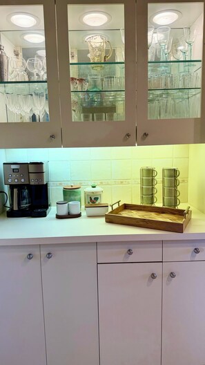Eine Küche mit Kaffeemaschine, einem Holztablett und dekorativer Glasware.
