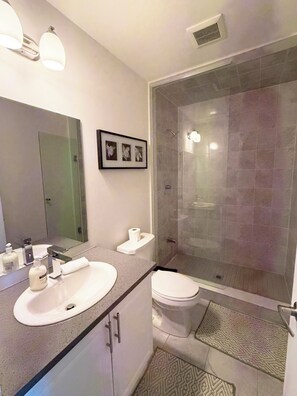A modern bathroom with a glass-enclosed shower, a sink with a mirror, and a toilet. - Great townhome in a family-friendly neighborhood (Ajax)