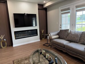 A modern living room with a flat-screen TV, a fireplace, a sofa, and a glass coffee table. - Great townhome in a family-friendly neighborhood (Ajax)
