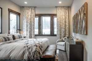 A bedroom with a large bed, a bench, a desk, and a window with curtains. - Sleek Mountain-Modern Townhome, Tucked in a Private Truckee Community (Truckee)