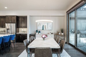 A modern kitchen with dark wood cabinets, stainless steel appliances, and a large dining table with chairs. - Sleek Mountain-Modern Townhome, Tucked in a Private Truckee Community (Truckee)