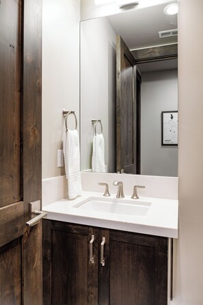 A bathroom with a white sink, two towel rings, and a large mirror. - Sleek Mountain-Modern Townhome, Tucked in a Private Truckee Community (Truckee)