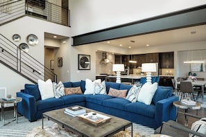 A modern living room with a sectional sofa, a coffee table, and a staircase. - Sleek Mountain-Modern Townhome, Tucked in a Private Truckee Community (Truckee)
