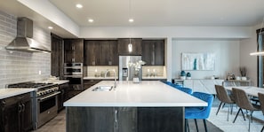 Una cocina moderna con alacenas de madera oscura, electrodomésticos de acero inoxidable y una isla grande con taburetes de bar.