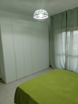 Une pièce comprenant un lit, une armoire et un luminaire suspendu.