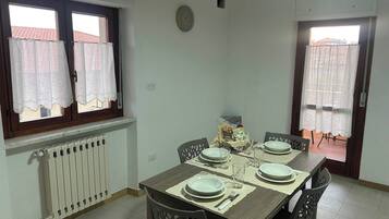 A dining room with a table set for four, a radiator, and a window with curtains.