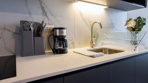 A modern kitchen with a built-in coffee maker, a sink, and a utensil holder. - Seminario Apartments by Andes STR (Ñuñoa)