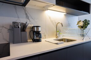 A modern kitchen with a built-in coffee maker, a sink, and a utensil holder. - Seminario Apartments by Andes STR (Ñuñoa)