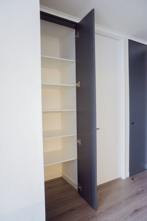 A room with a built-in closet featuring multiple shelves and a sliding door. - Seminario Apartments by Andes STR (Ñuñoa)