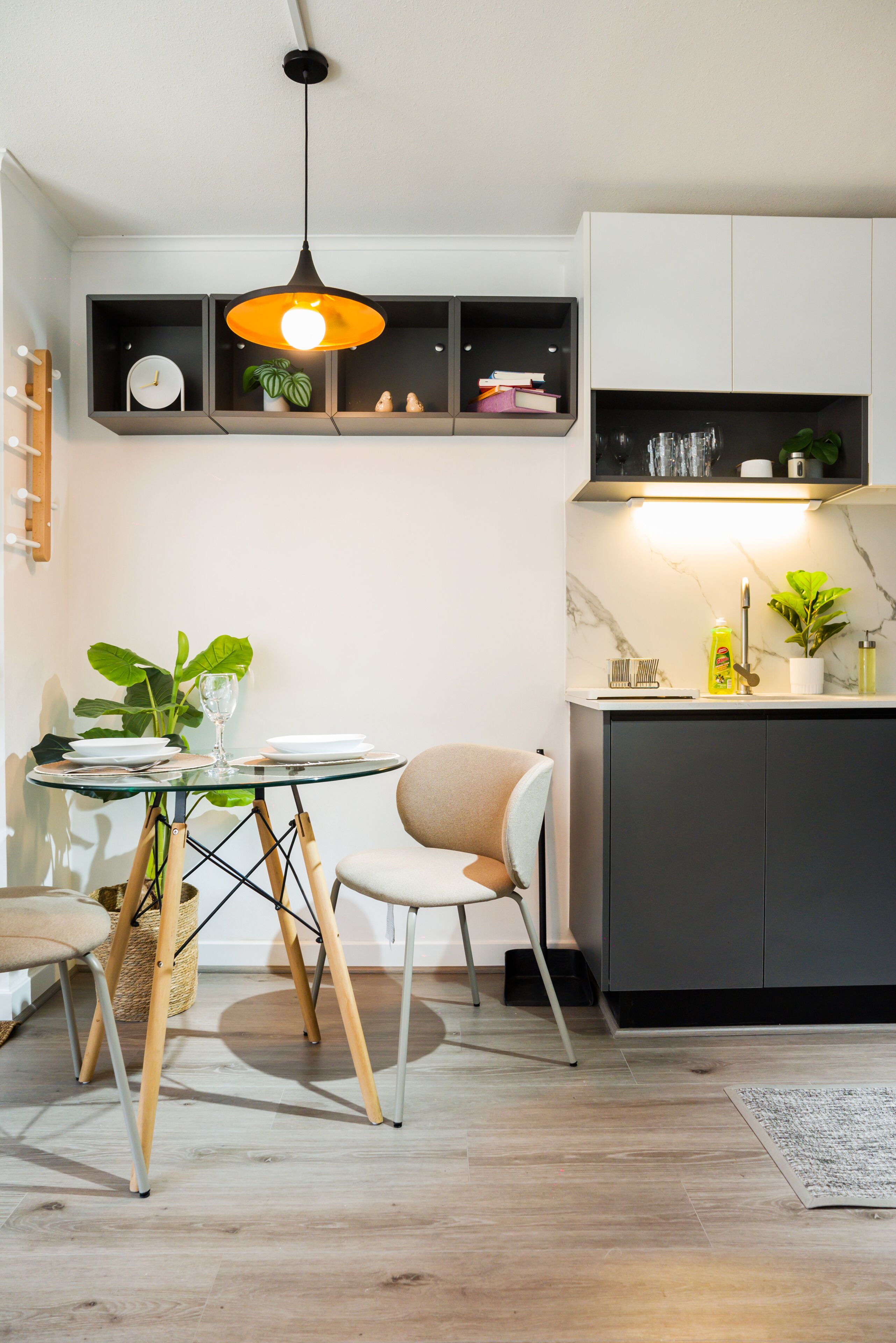 Una cocina moderna con comedor, que incluye una mesa de vidrio, sillas y una lámpara colgante.