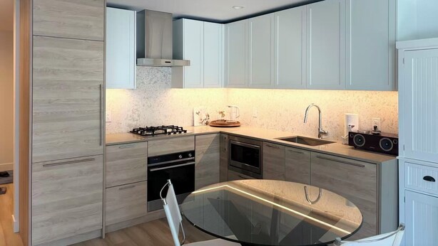 Una cocina moderna con estufa a gas, horno, microondas y una mesa de comedor de vidrio.
