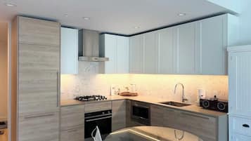 A modern kitchen with a gas stove, oven, microwave, and a glass dining table.