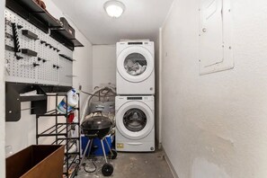A laundry room with two stacked washing machines, a pegboard with various tools, and a portable heater. - Spacious 4BR | Near UF & Shands | Pool + Gym (Gainesville)