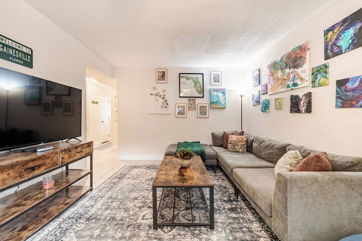 Ein Wohnzimmer mit Fernseher, Sofa, Couchtisch und Kunstwerken an den Wänden.