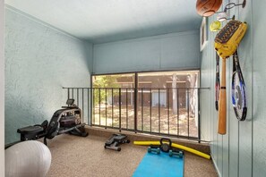 A home gym with exercise equipment, a blue mat, and sports balls. - Spacious 4BR | Near UF & Shands | Pool + Gym (Gainesville)