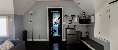 A compact living space with a kitchenette, a sofa, a coffee table, and a decorative door.