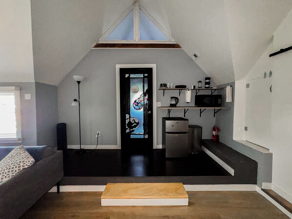 A compact living space with a kitchenette, a sofa, a coffee table, and a decorative door.