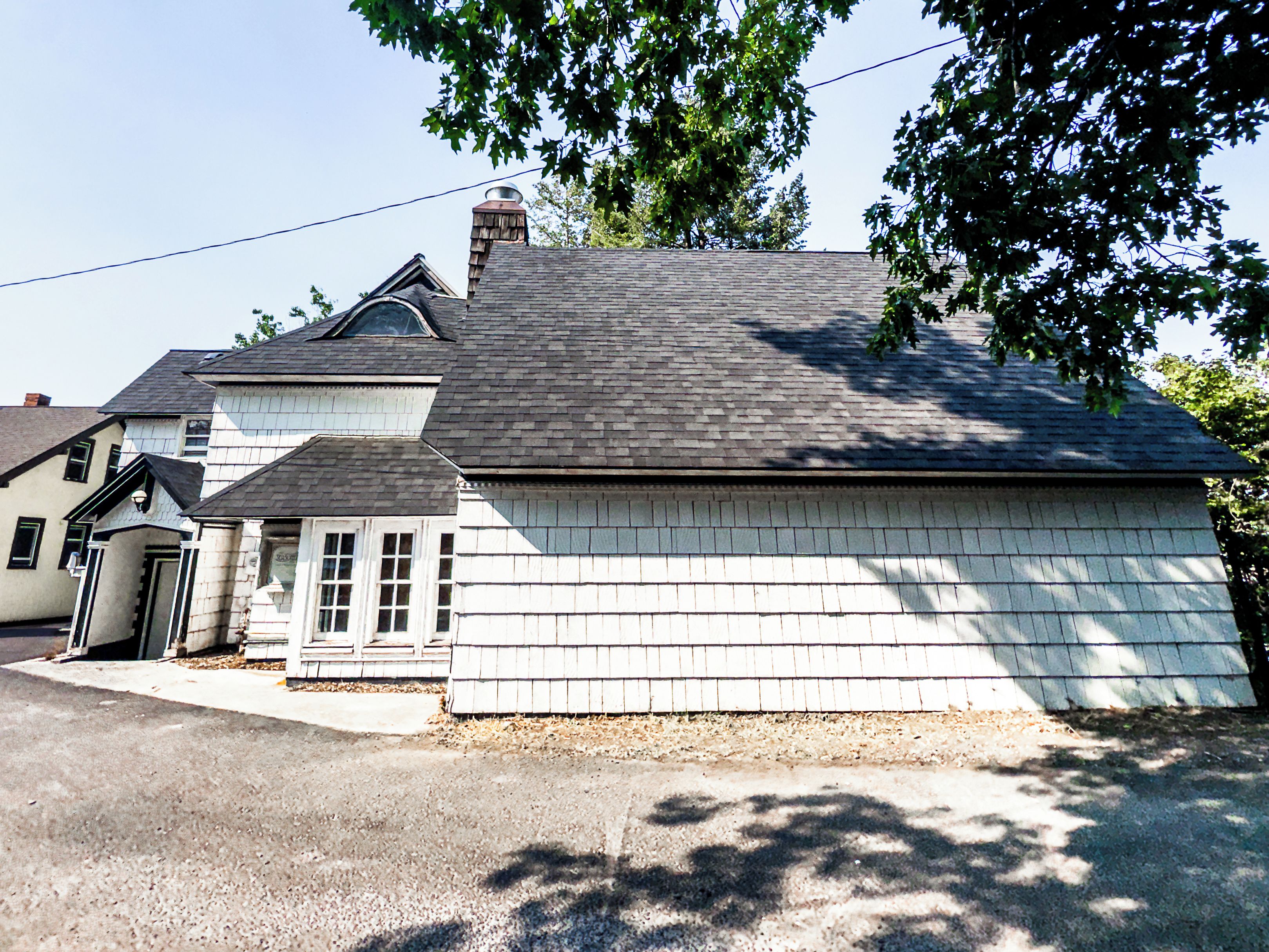 Une maison à deux étages avec une cheminée, un garage et une allée.
