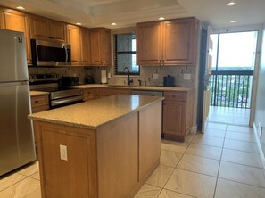 A modern kitchen with wooden cabinets, stainless steel appliances, and a large island. - 2-bedroom apt BEACHFRONT on Marco Island - Eagle's Nest Resort PRESIDENT'S WEEK! (Marco Island)