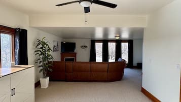 A spacious living area with a ceiling fan, a large window, a sofa, and a potted plant.