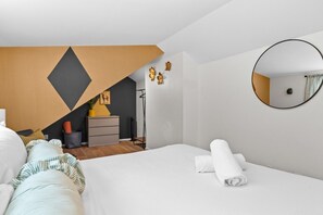 A modern bedroom with a bed, a dresser, a mirror, and a geometric wall design. - 3 Levels of Living 2 Lounges, 2 K Suites + Pool Table E ATX Outdoor Living (Austin)