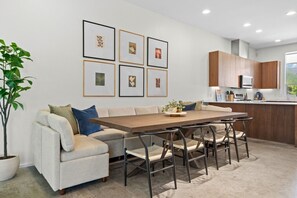 A modern kitchen with wooden cabinets, a dining area with a table and chairs, and a sofa with cushions. - 3 Levels of Living 2 Lounges, 2 K Suites + Pool Table E ATX Outdoor Living (Austin)