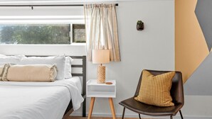 A bedroom with a bed, bedside table, lamp, chair, and a view of trees through the window. - 3 Levels of Living 2 Lounges, 2 K Suites + Pool Table E ATX Outdoor Living (Austin)