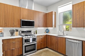 Eine moderne Küche mit Holzschränken, Edelstahlgeräten und einem Fenster, das für natürliches Licht sorgt.
