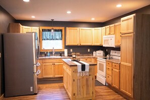 A kitchen with wooden cabinets, a refrigerator, a microwave, an oven, and a sink. - 3BR/2BA • 4-6 Min to Huzzah Valley & Bass River Resort (Steelville)