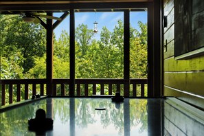 Ein Zimmer mit großem Fenster, einer Holzdiele und Blick auf Bäume.