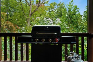 A black outdoor grill with a digital display, positioned on a wooden deck with a railing. - Peaceful Wooded Retreat - Arcade, Hot Tub + Fire Pit (Sevierville)