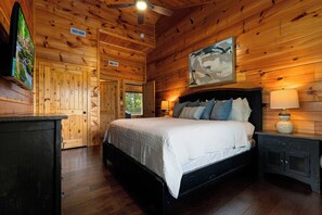 Ein Holzblockhaus-Interieur mit einem Bett, Nachttischlampen und einem Bild an der Wand.
