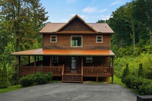 Eine zweistöckige Blockhütte mit Veranda und überdachter Eingangstür.