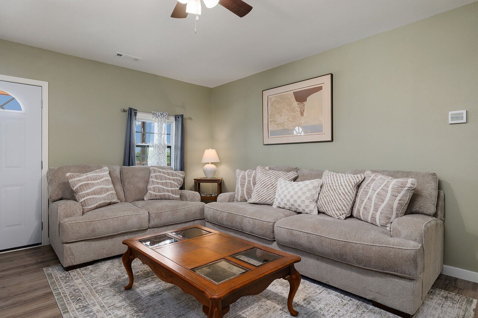 A living room with a sectional sofa, a wooden coffee table, a lamp, and a framed picture on the wall.