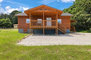 A wooden cabin with a covered porch and a staircase leading to an upper level.