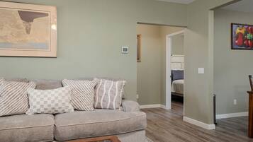 A living room with a sofa, a coffee table, and a painting on the wall.